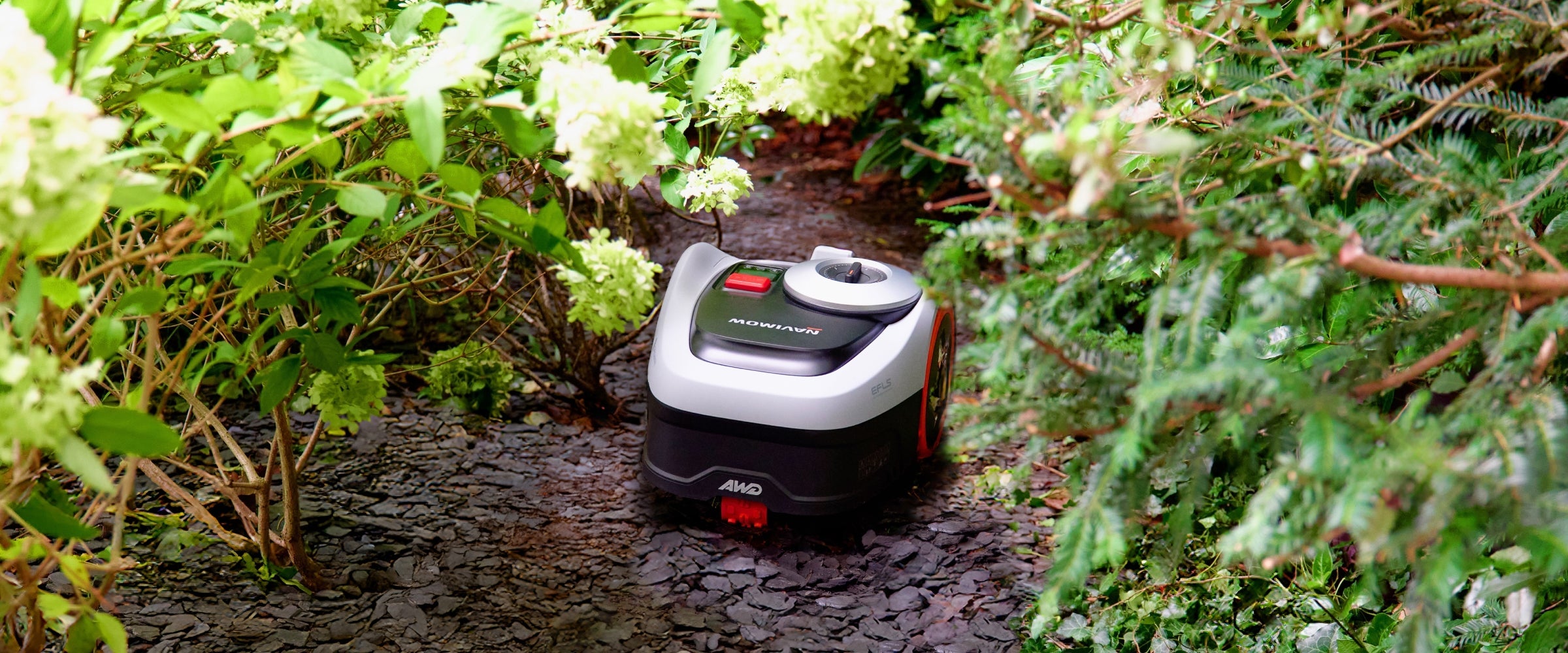 Navimow i110N robot lawn mower is seen in a garden.