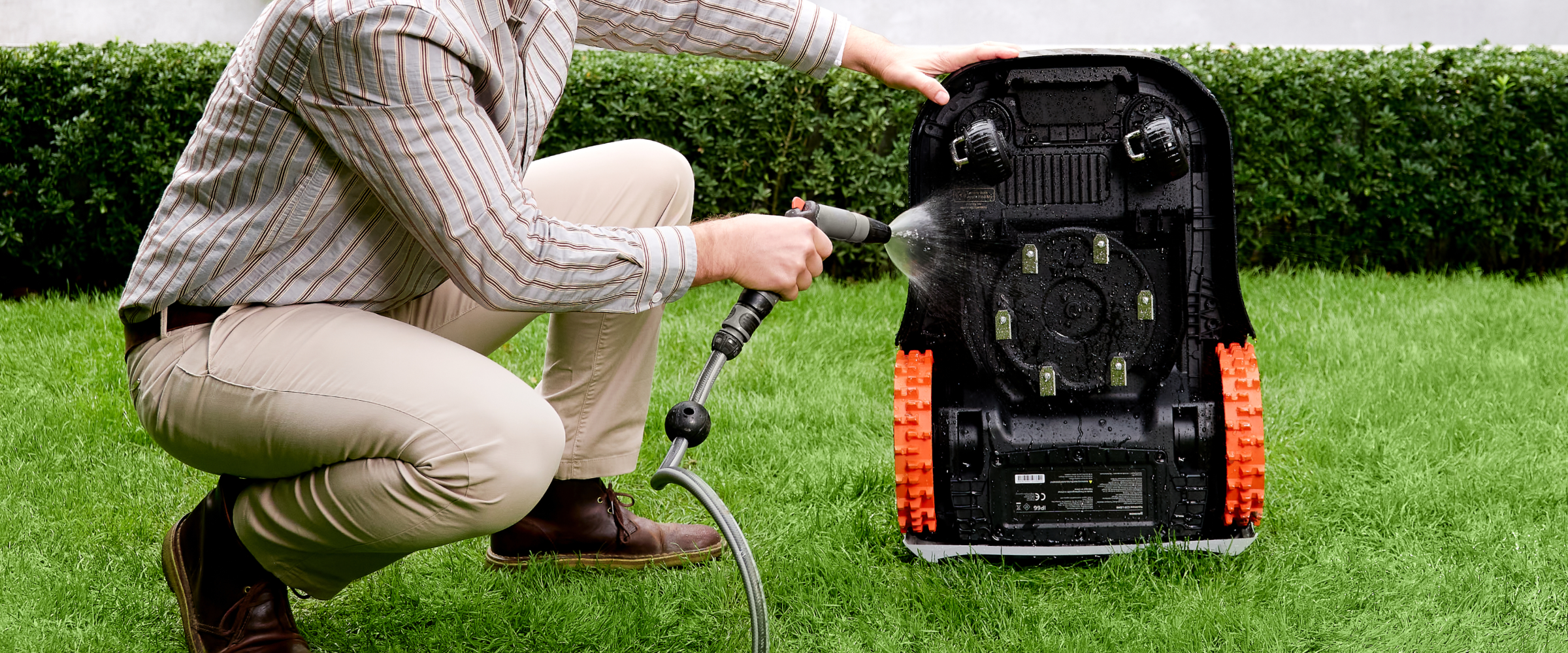 Navimow i105E robot lawn mower is being cleaned with water.