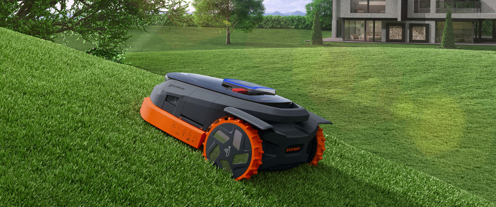 Segway Navimow robot lawn mower mows a green grassy hill.