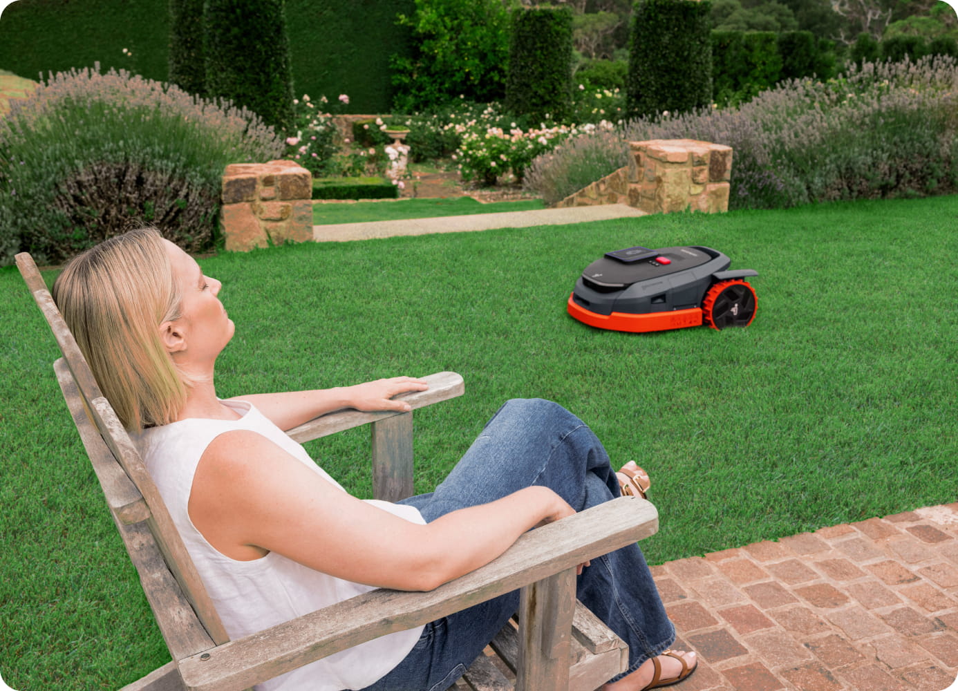 Navimow i110N robot lawn mower cuts grass while woman relaxes.