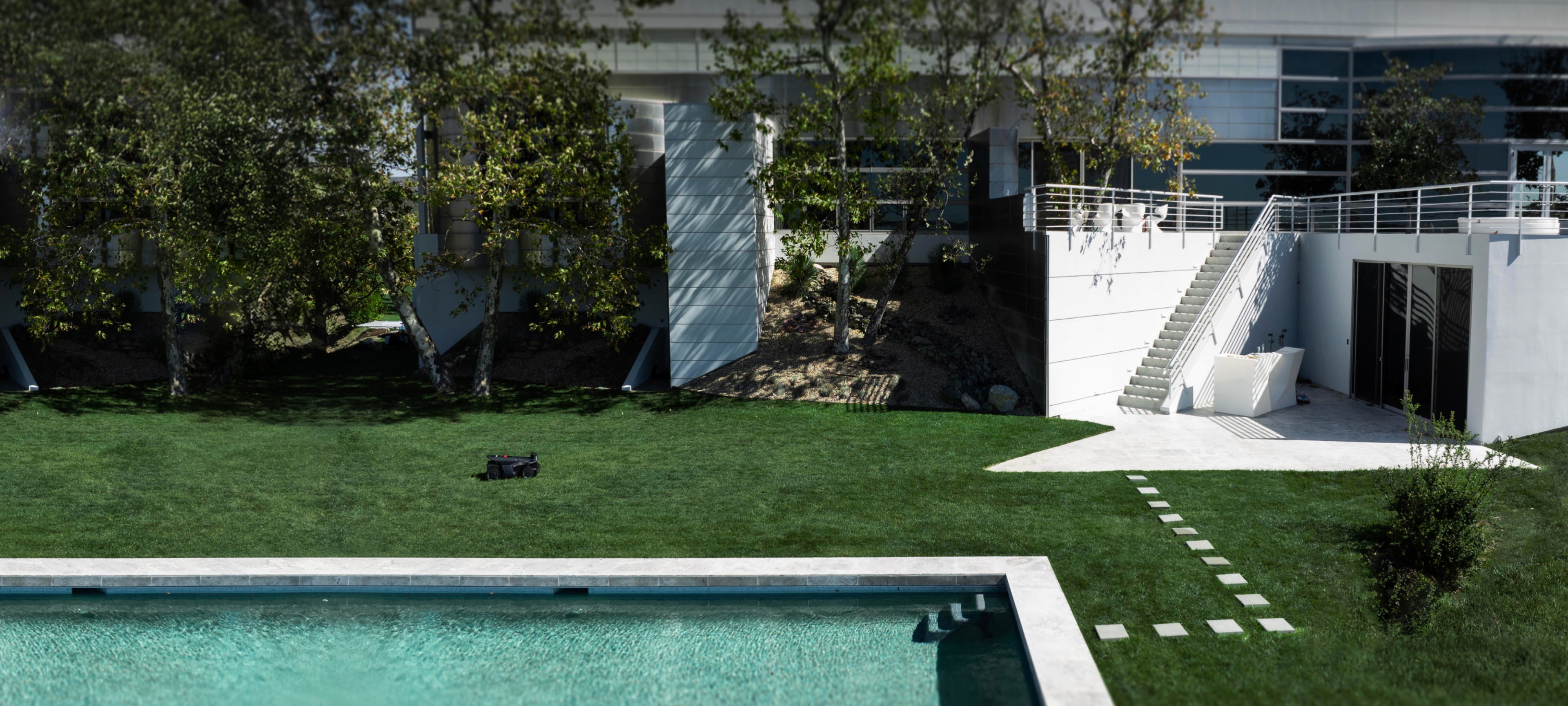 Navimow i110N robot lawn mower mows grass near a pool.