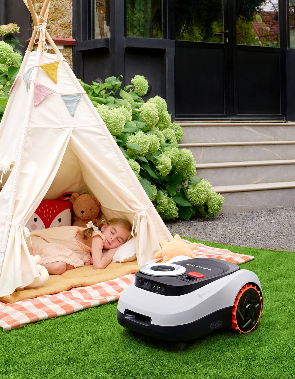 Segway Navimow robot lawn mower next to a sleeping girl.