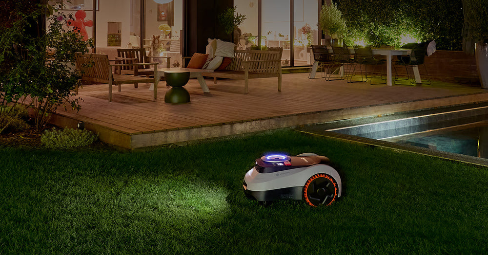 Segway Navimow i110N robot lawn mower mows grass at night.