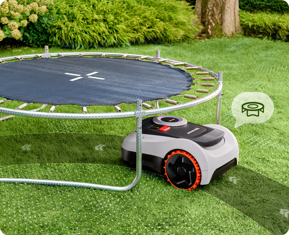 Segway Navimow robot lawn mower mows grass under a trampoline.