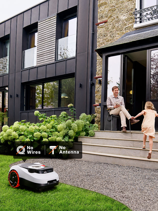 Navimow i110E robot lawn mower on grass near a family.