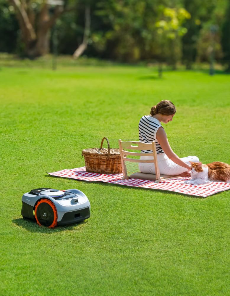 Navimow i110E robot lawn mower near woman and ginger cat.