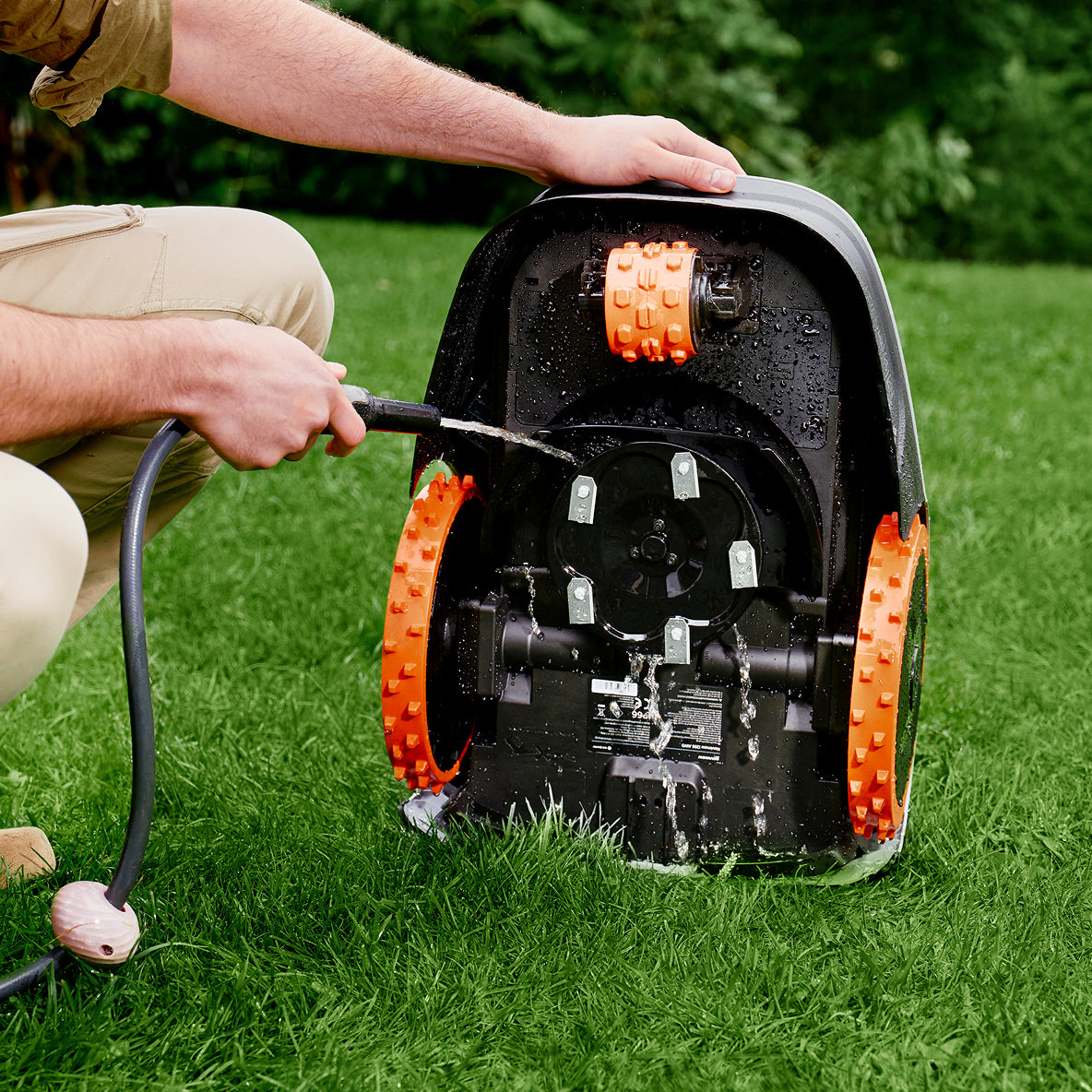 Navimow i105E robot lawn mower being cleaned by a man.
