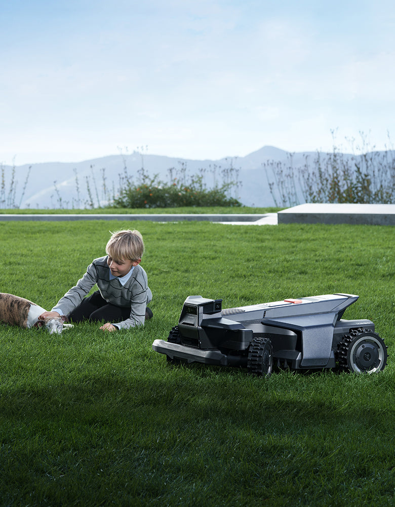 Navimow i105 robot lawn mower beside a boy and dog