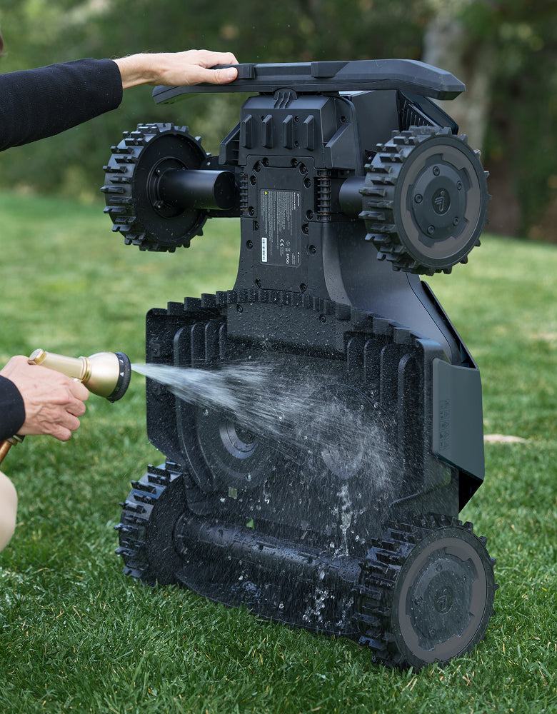 Navimow i110E robot lawn mower being washed with a hose.